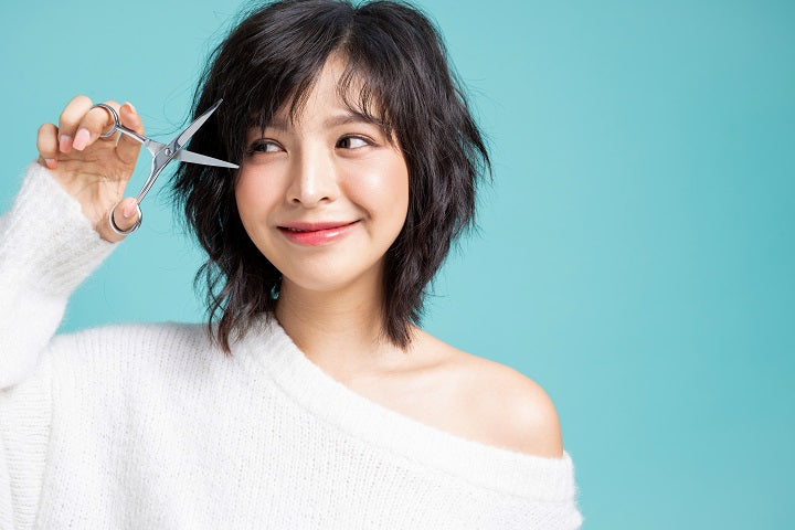 kobieta z nożyczkami pokazująca jak obciąć grzywkę